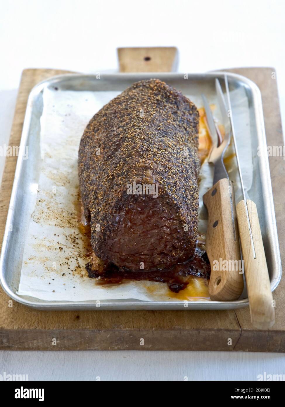 Roast fillet of beef with pepper coating in roasting tin Stock Photo