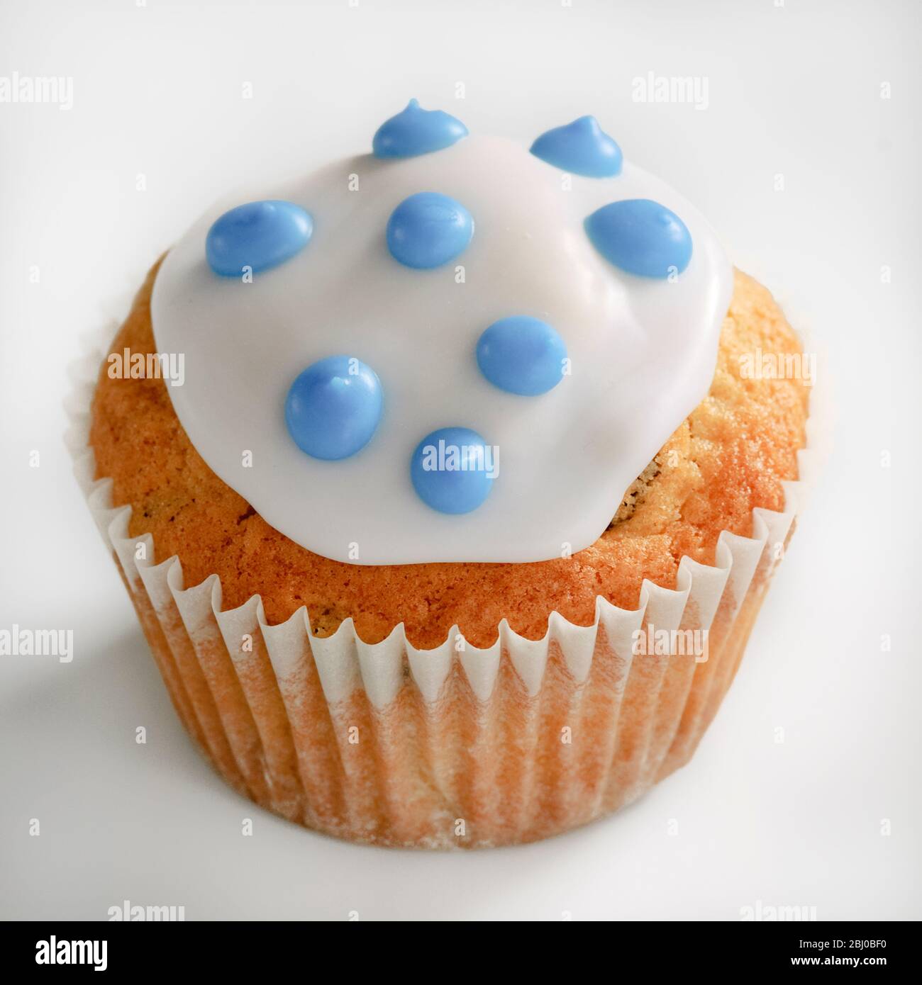 Iced cupcake with blue spots on white icing - Stock Photo