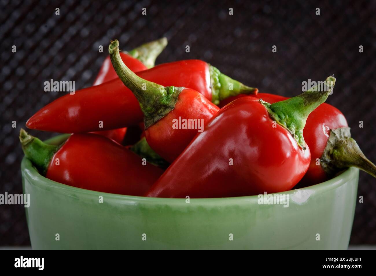 Shiny red chilli peppers in green bowl - Stock Photo