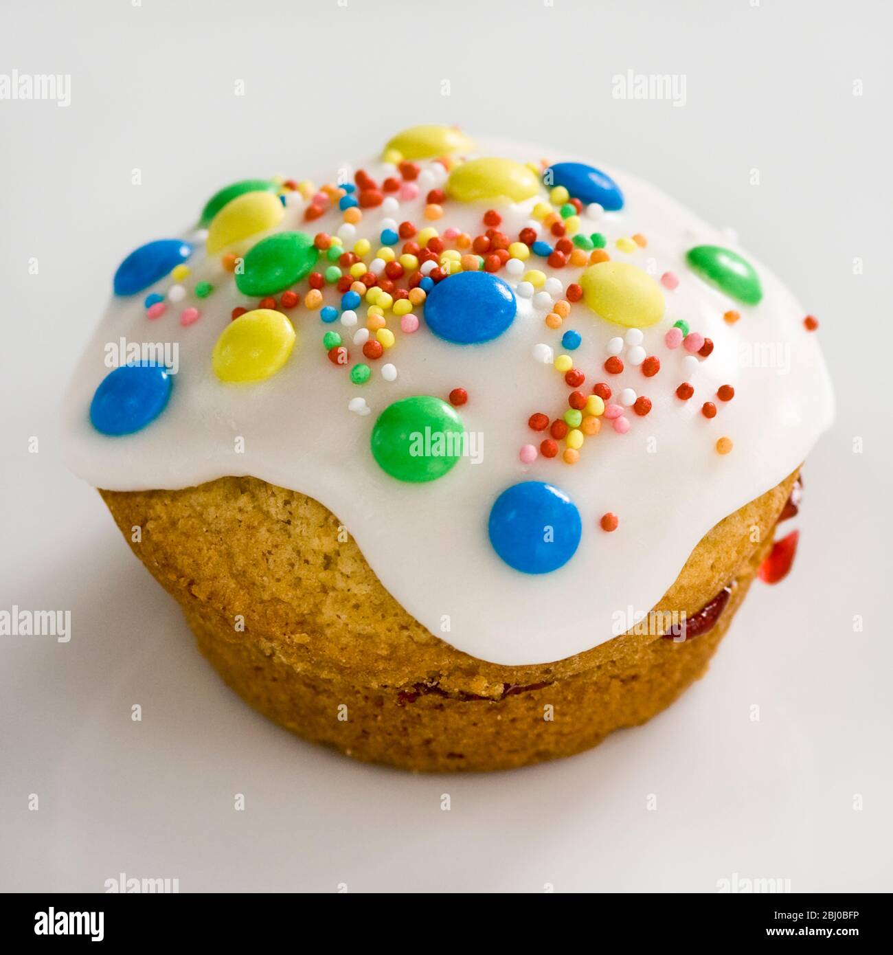 Muffin with icing topping with M&Ms and streusel sprinkles - Stock Photo