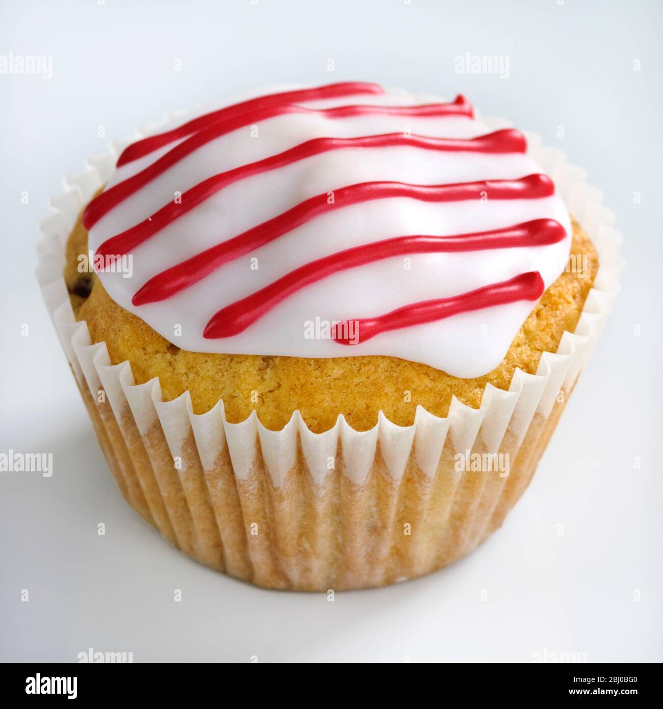 Iced cupcake with red stripes on white icing - Stock Photo