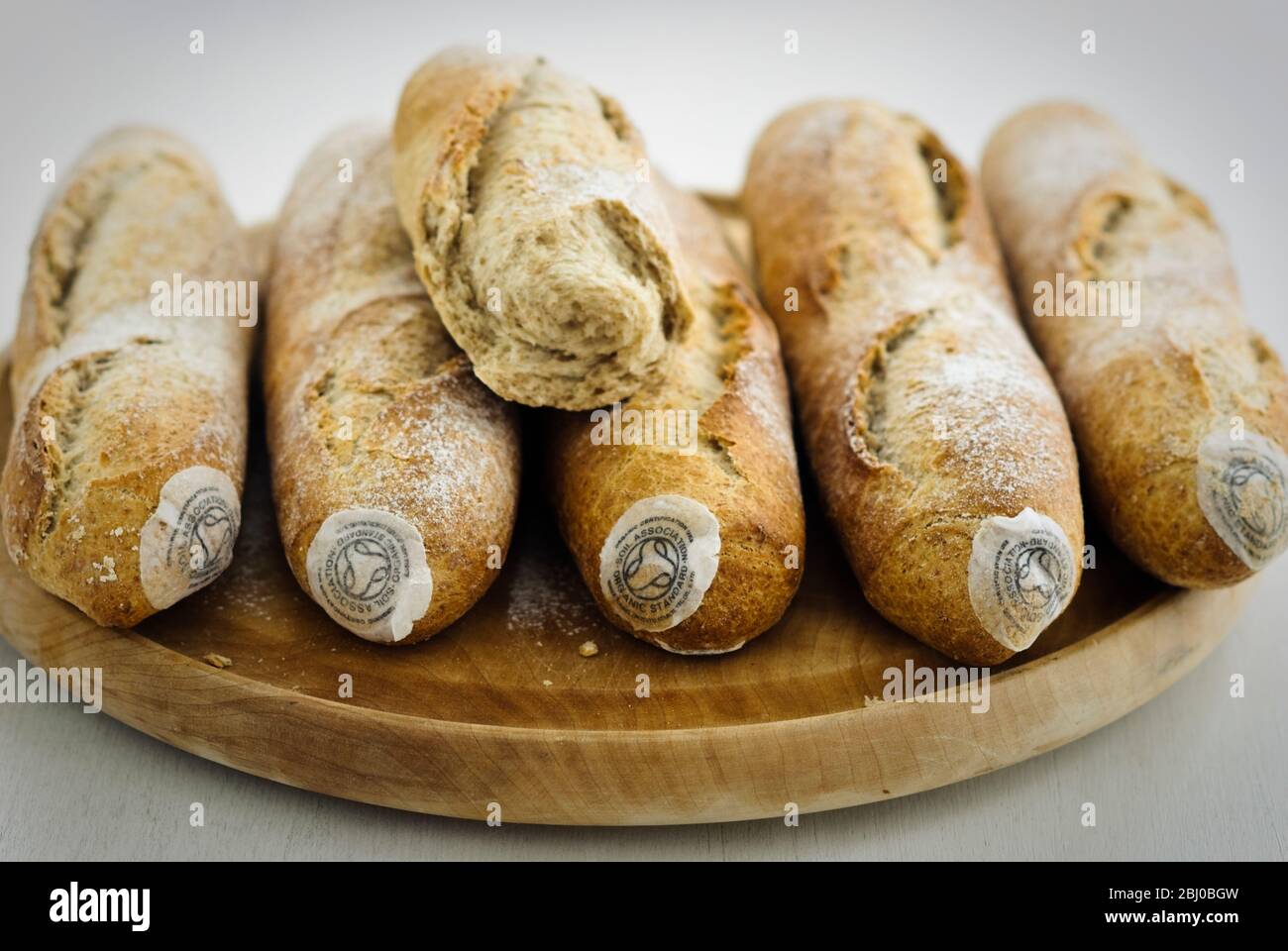 Pile of stoneground wholemeal organic baguettes on woden board - Stock Photo