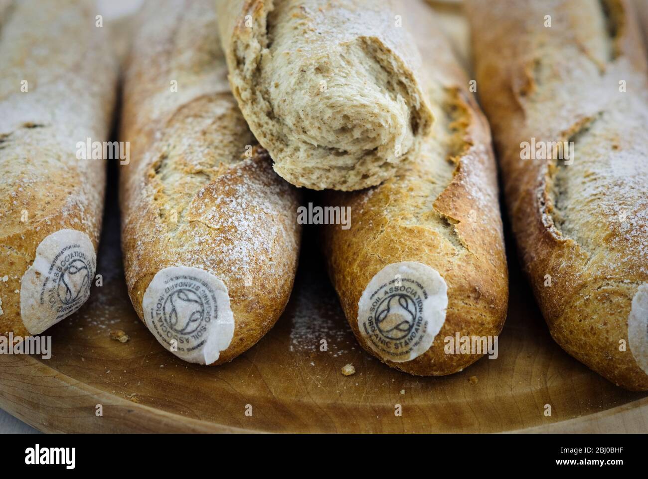 Pile of stoneground wholemeal organic baguettes on woden board - Stock Photo