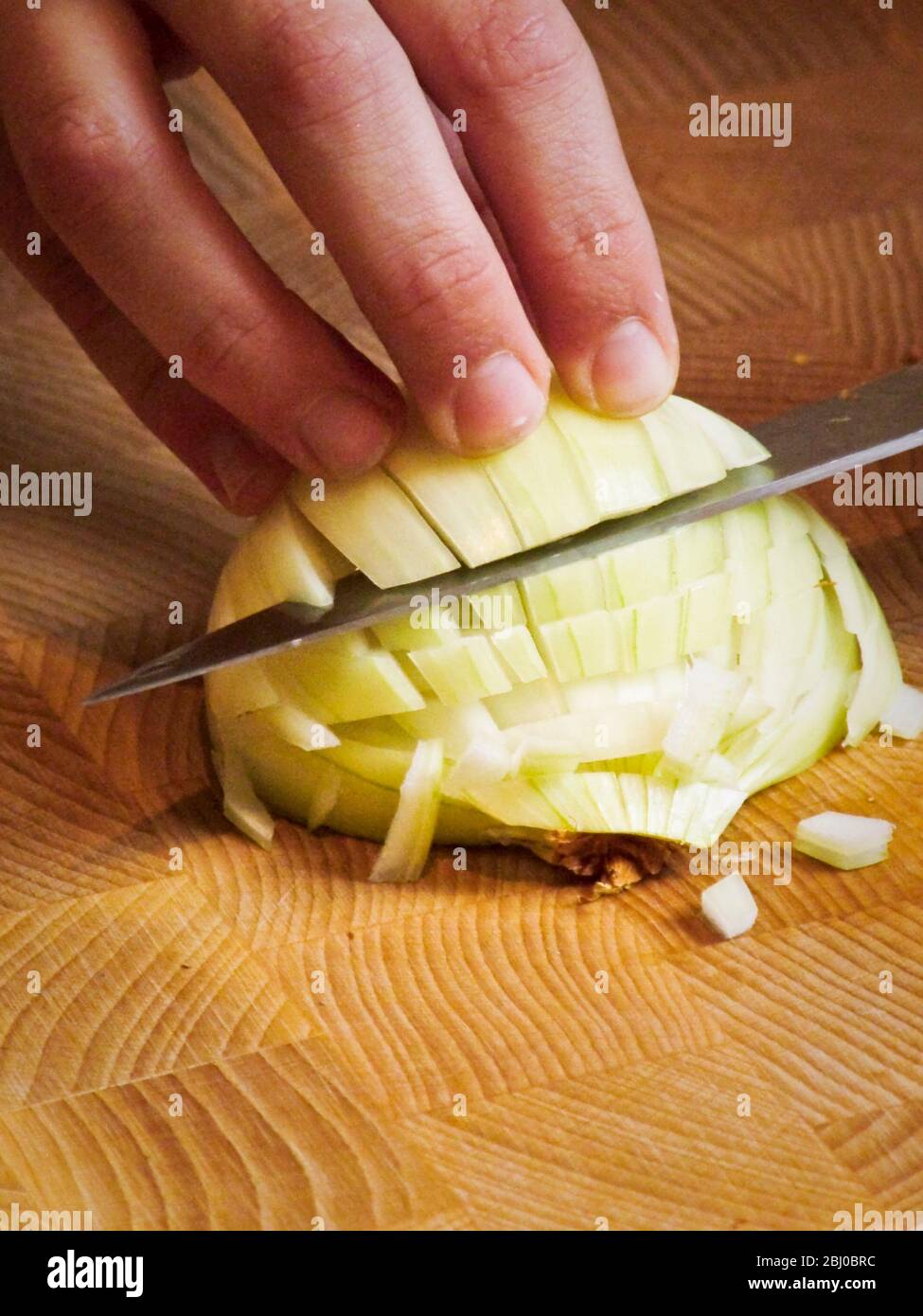 Child learning to chop an onion - Stock Photo