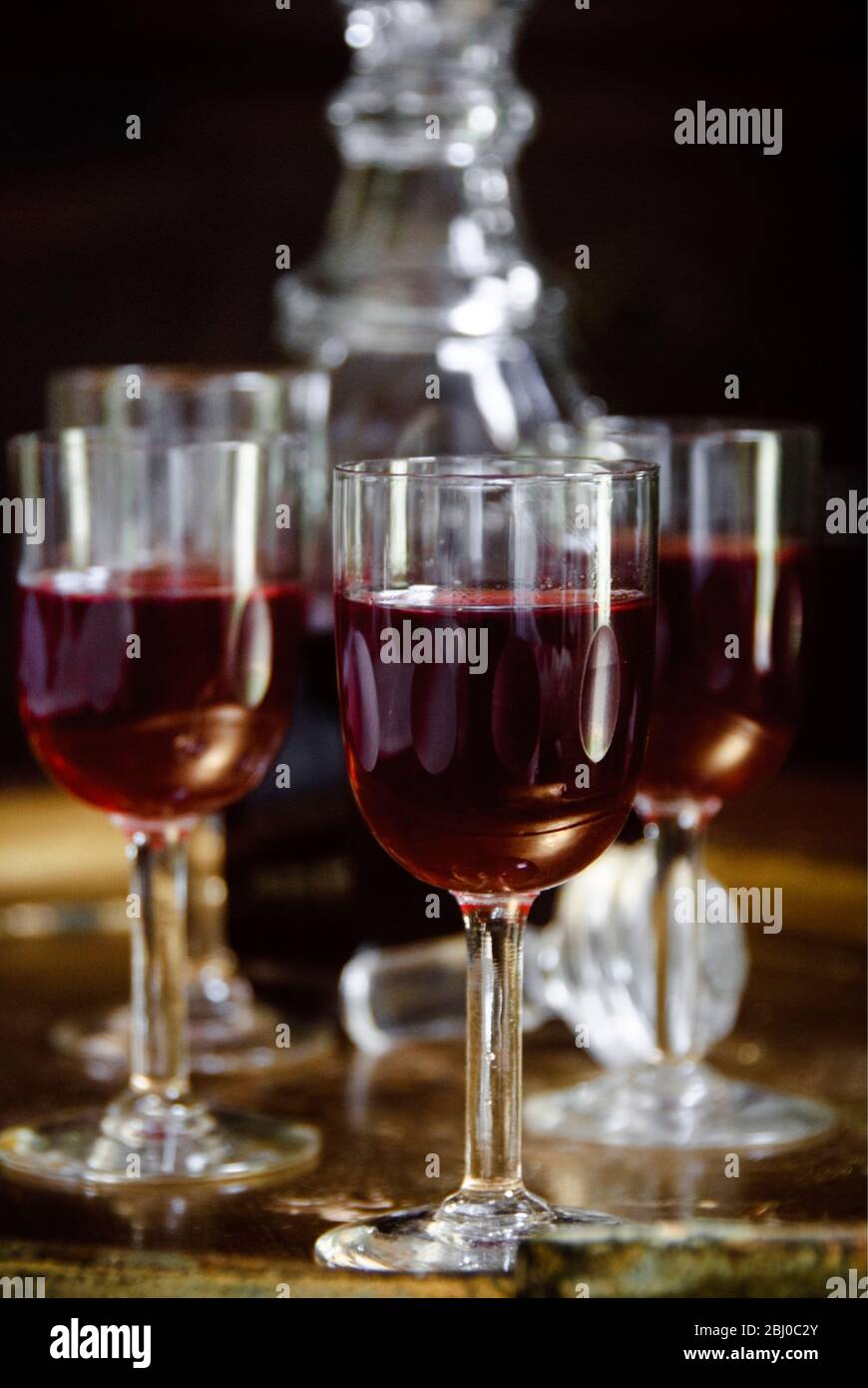 A tray of glasses of sloe gin with unstoppered decanter. - Stock Photo
