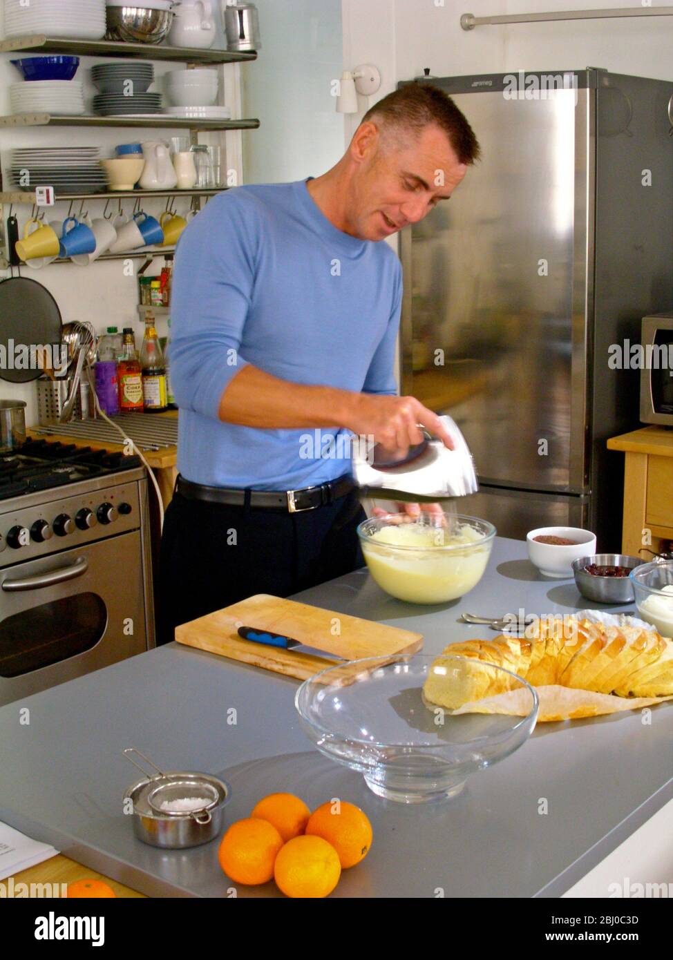 Gary Rhodes in domestic kitchen whisking ingredients for a festive bread and butter pudding - Stock Photo