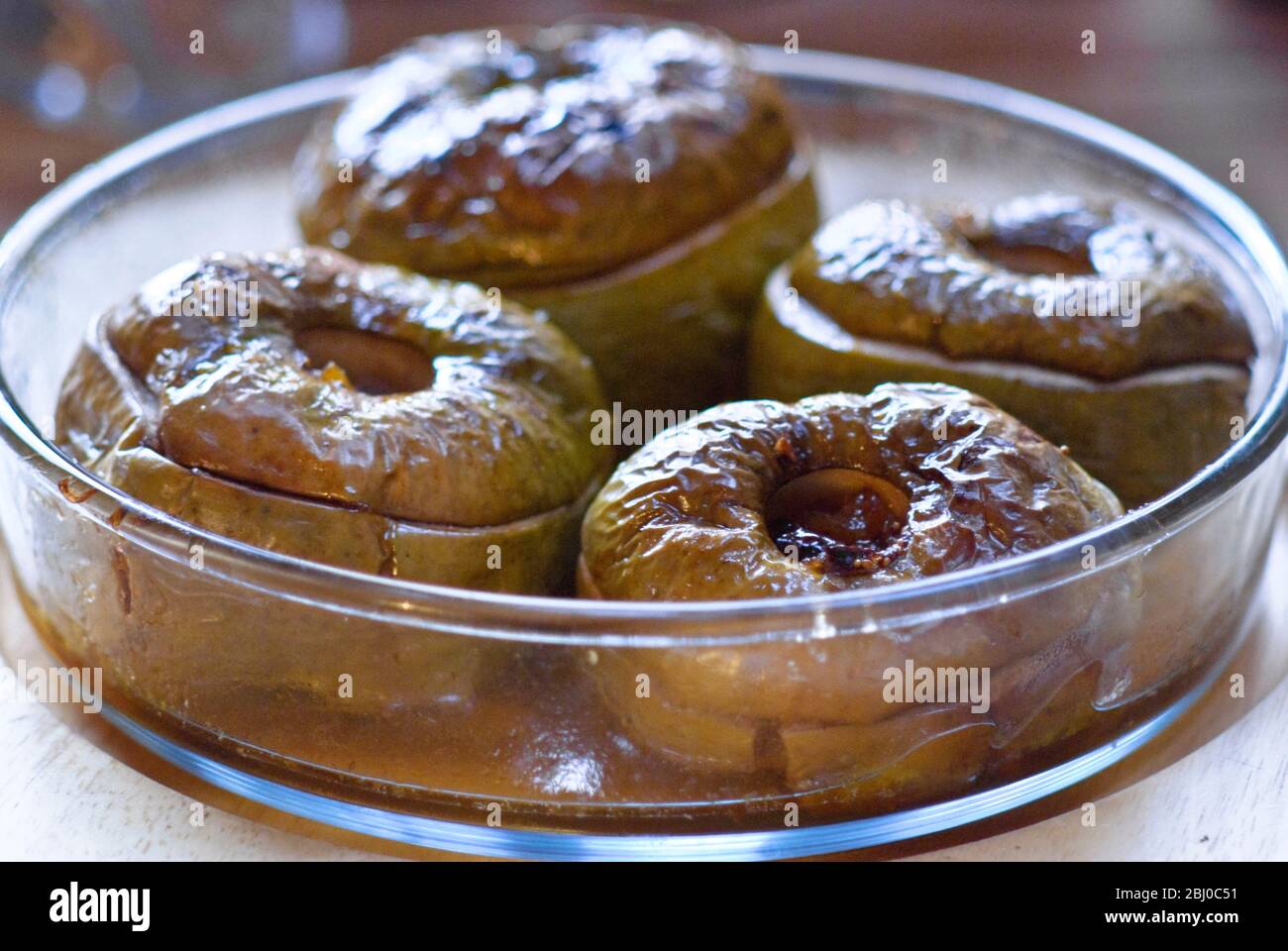 Four baked apples in glass dish - Stock Photo