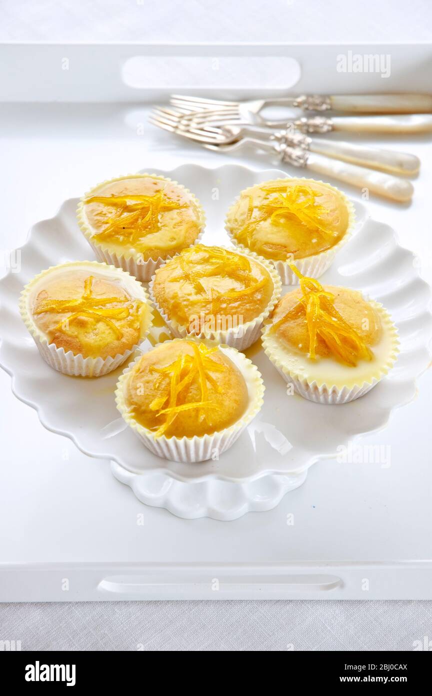 Six lemon drizzle fairy cakes on white cake stand - Stock Photo
