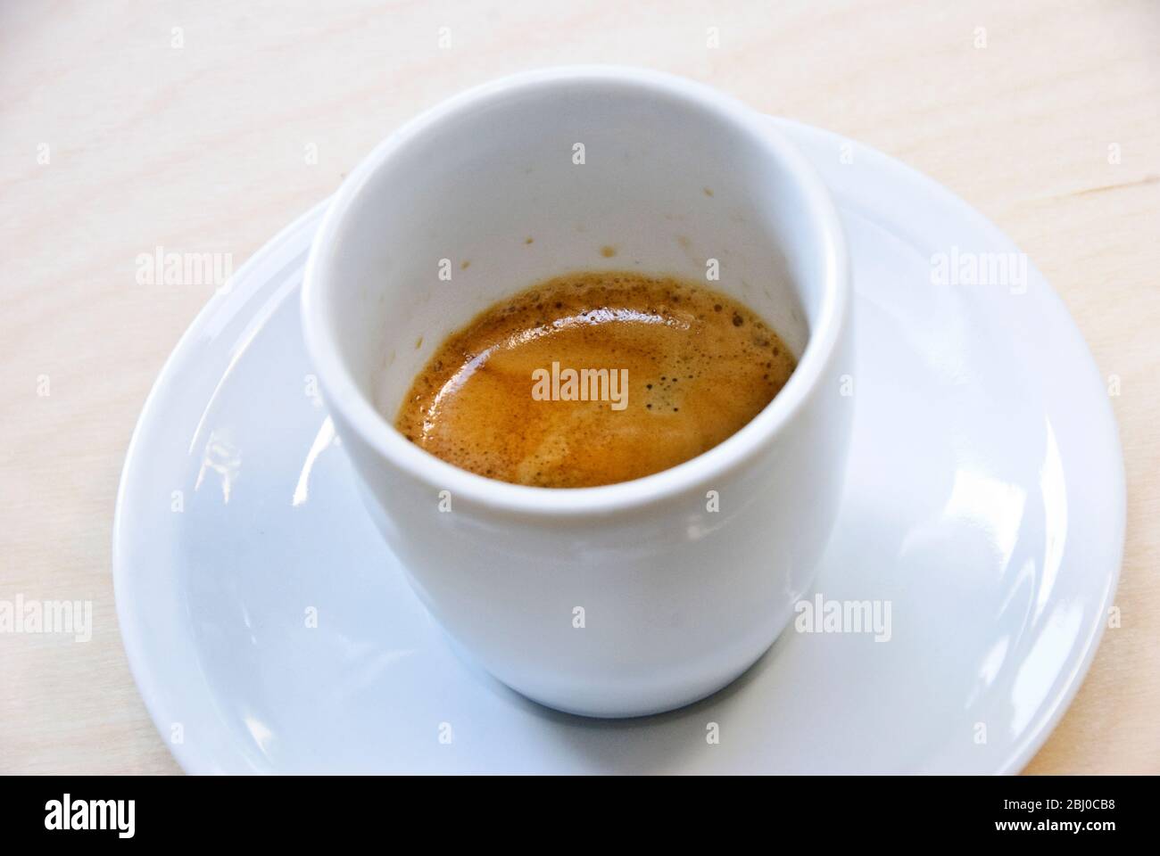 White porcelain cup of freshly brewed espresso coffee shoeing 'crema' - Stock Photo