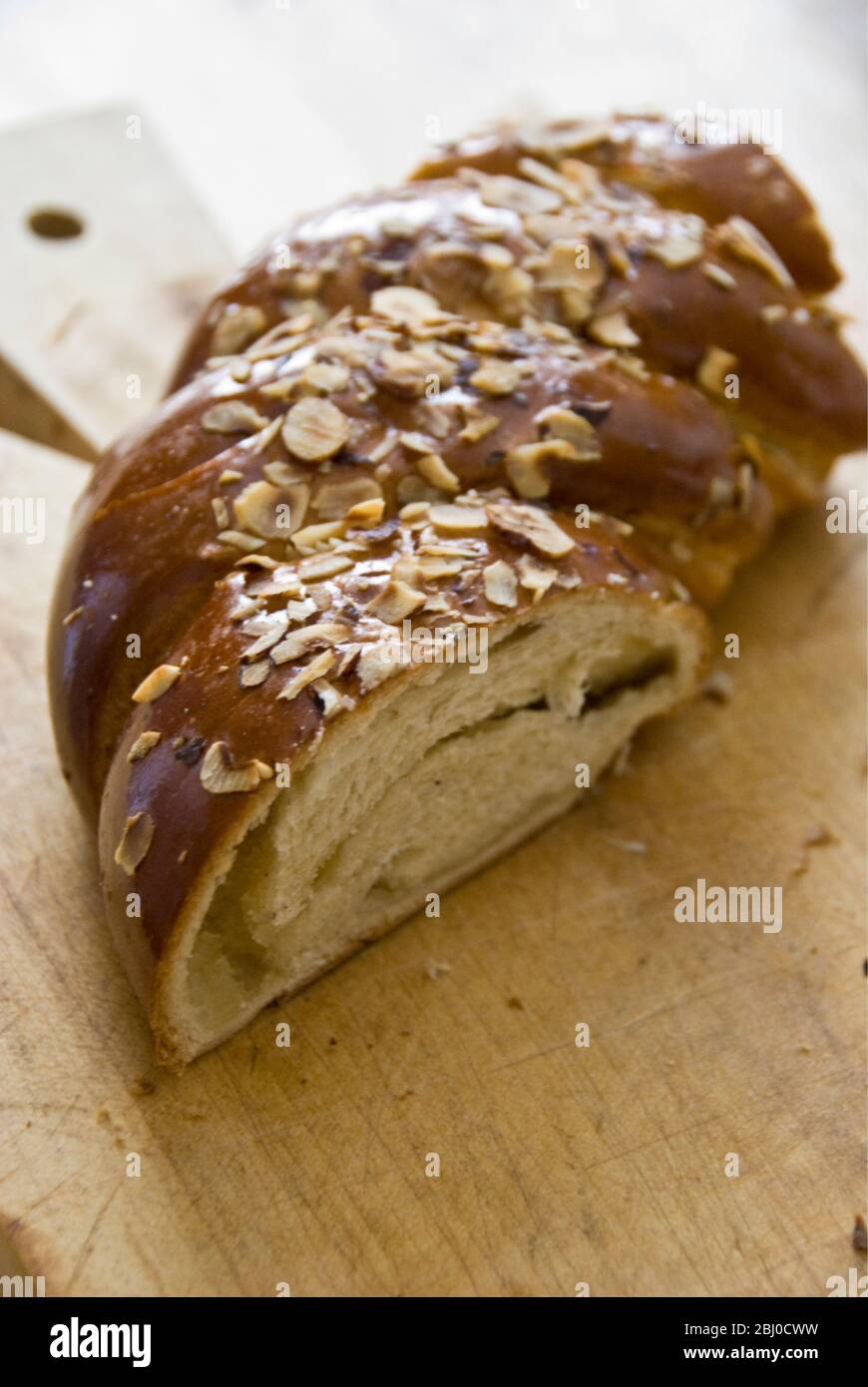 Piece of sweet, yeast bread with almonds and almond paste on wooden board - Stock Photo