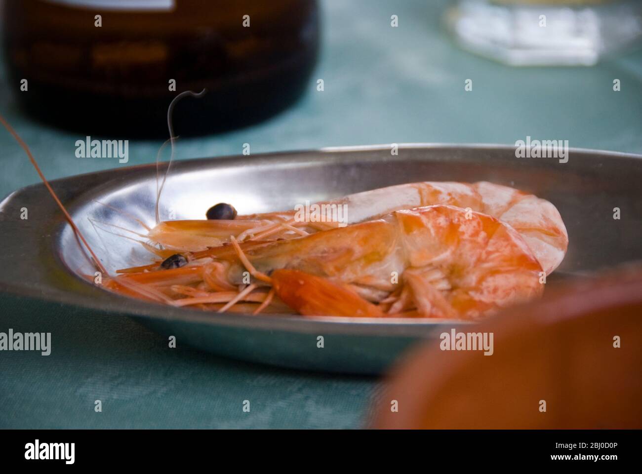 Large prawns in stainless steel dish on table of Greek Cypriot seafood restaurant in Larnaca, southern Cyprus - Stock Photo