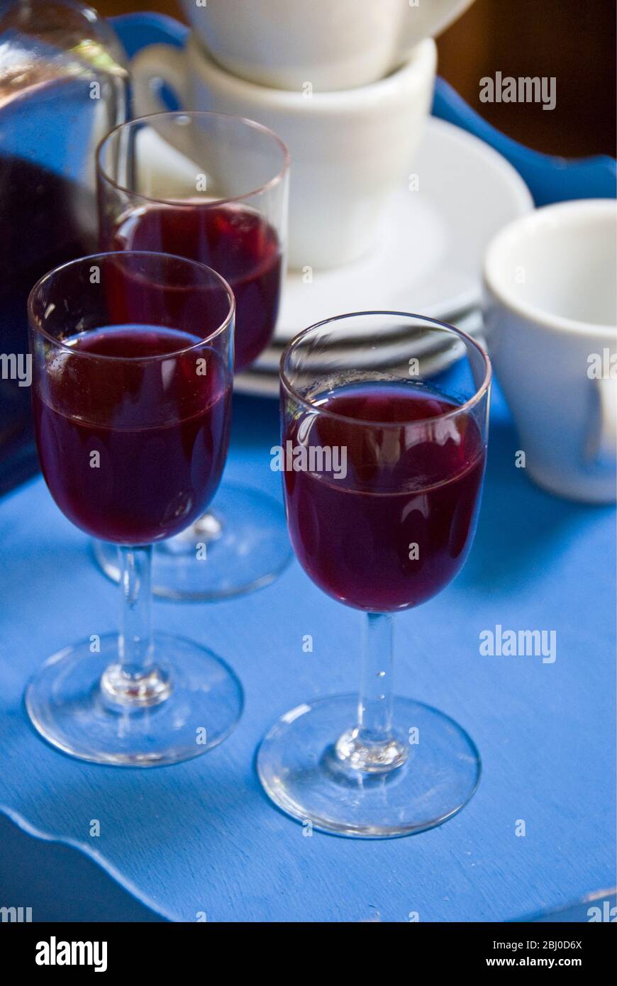 Small glasses of homemade sloe gin to be served with coffee. - Stock Photo
