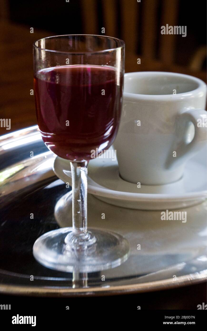 Glass of sloe gin with cup of after dinner coffee - Stock Photo
