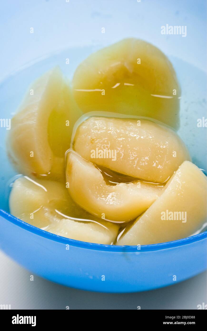 Canned Bartlett pears opened and turned into a blue bowl - Stock Photo