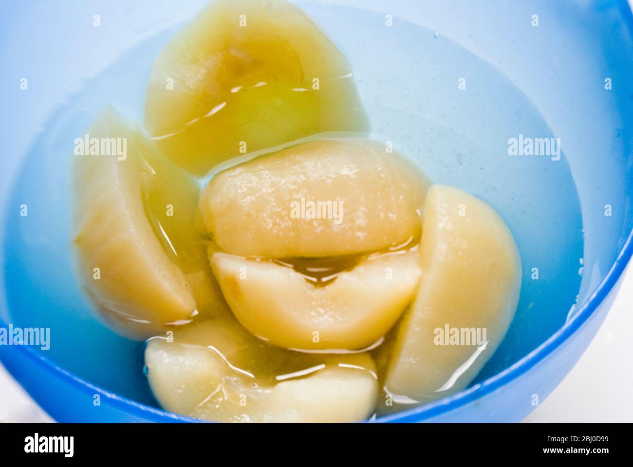Canned Bartlett pears opened and turned into a blue bowl - Stock Photo