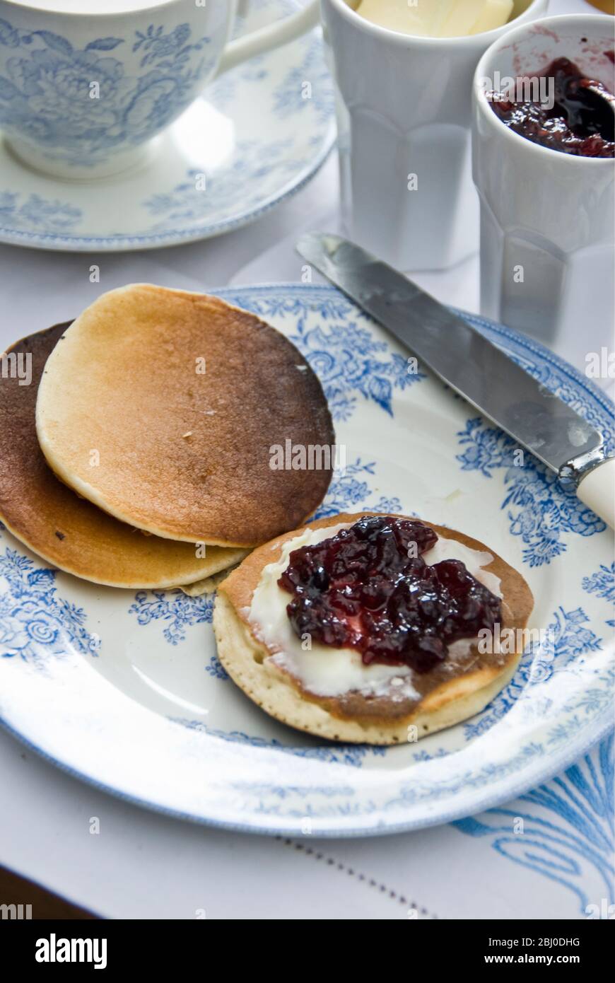 Teatime setting with scotch pancakes and raspberry jam - Stock Photo