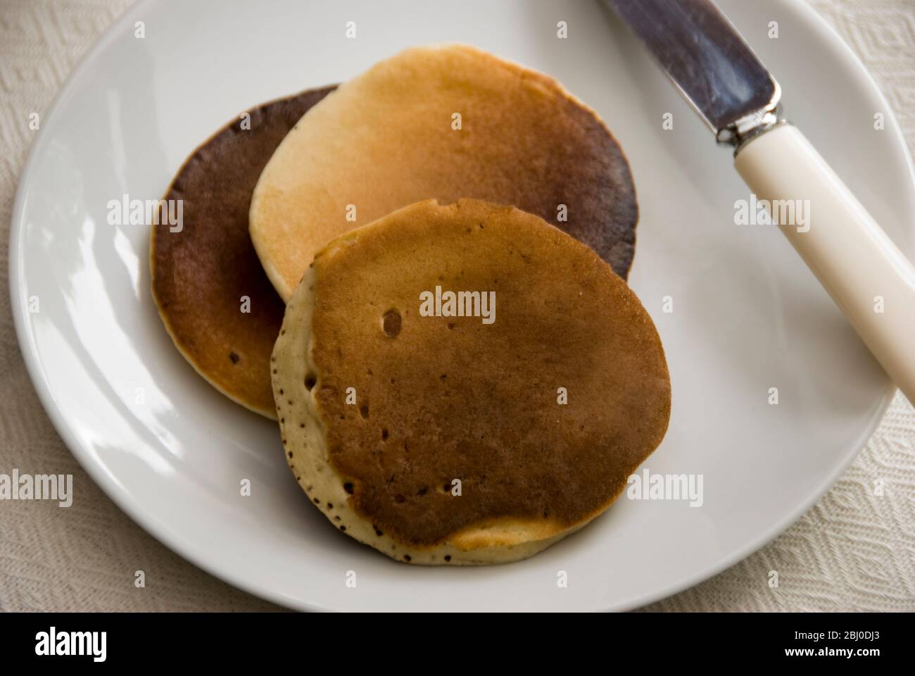 Three Scotch pancakes on a white plate. - Stock Photo