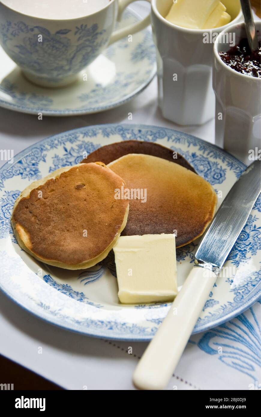 Teatime setting with scotch pancakes and raspberry jam - Stock Photo