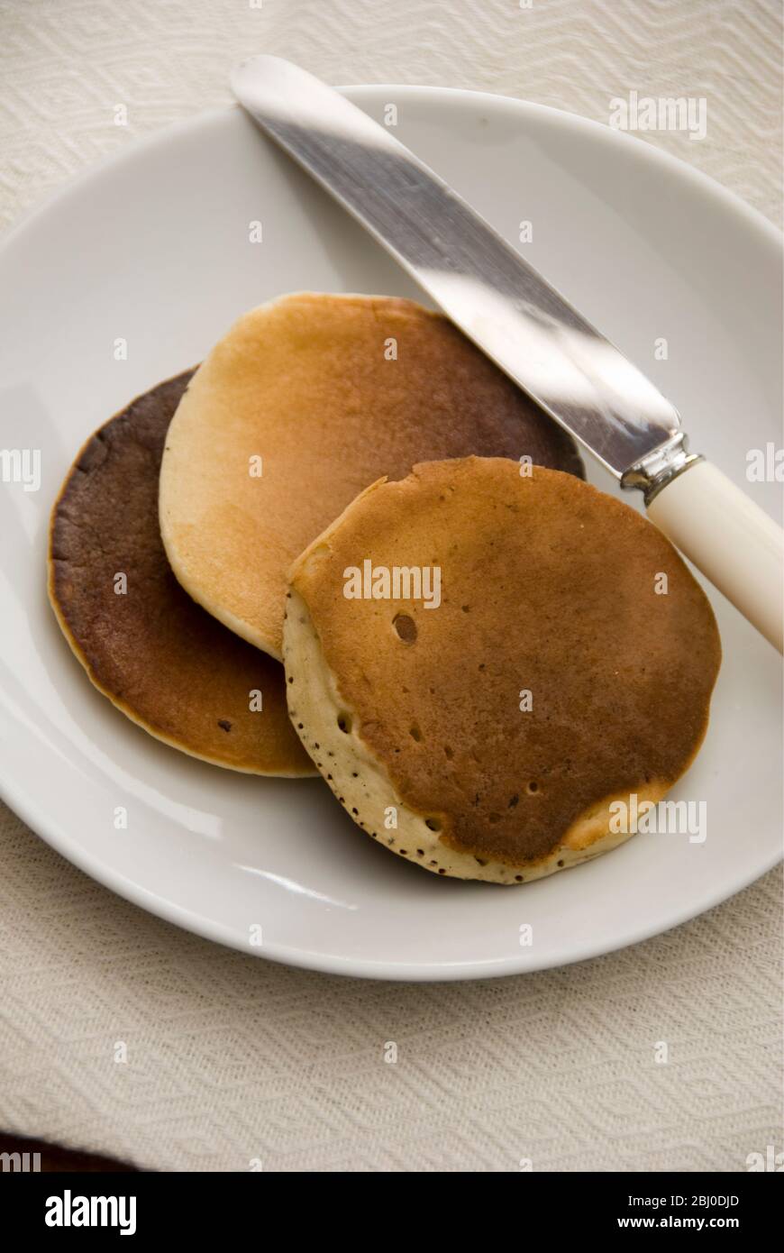 Three Scotch pancakes on a white plate. - Stock Photo