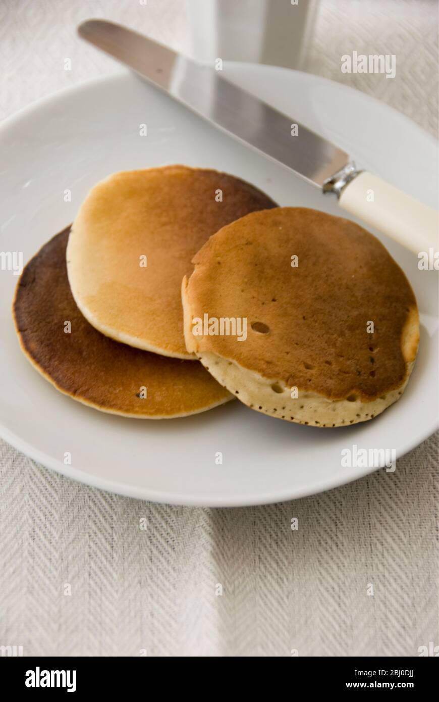 Three Scotch pancakes on a white plate - Stock Photo