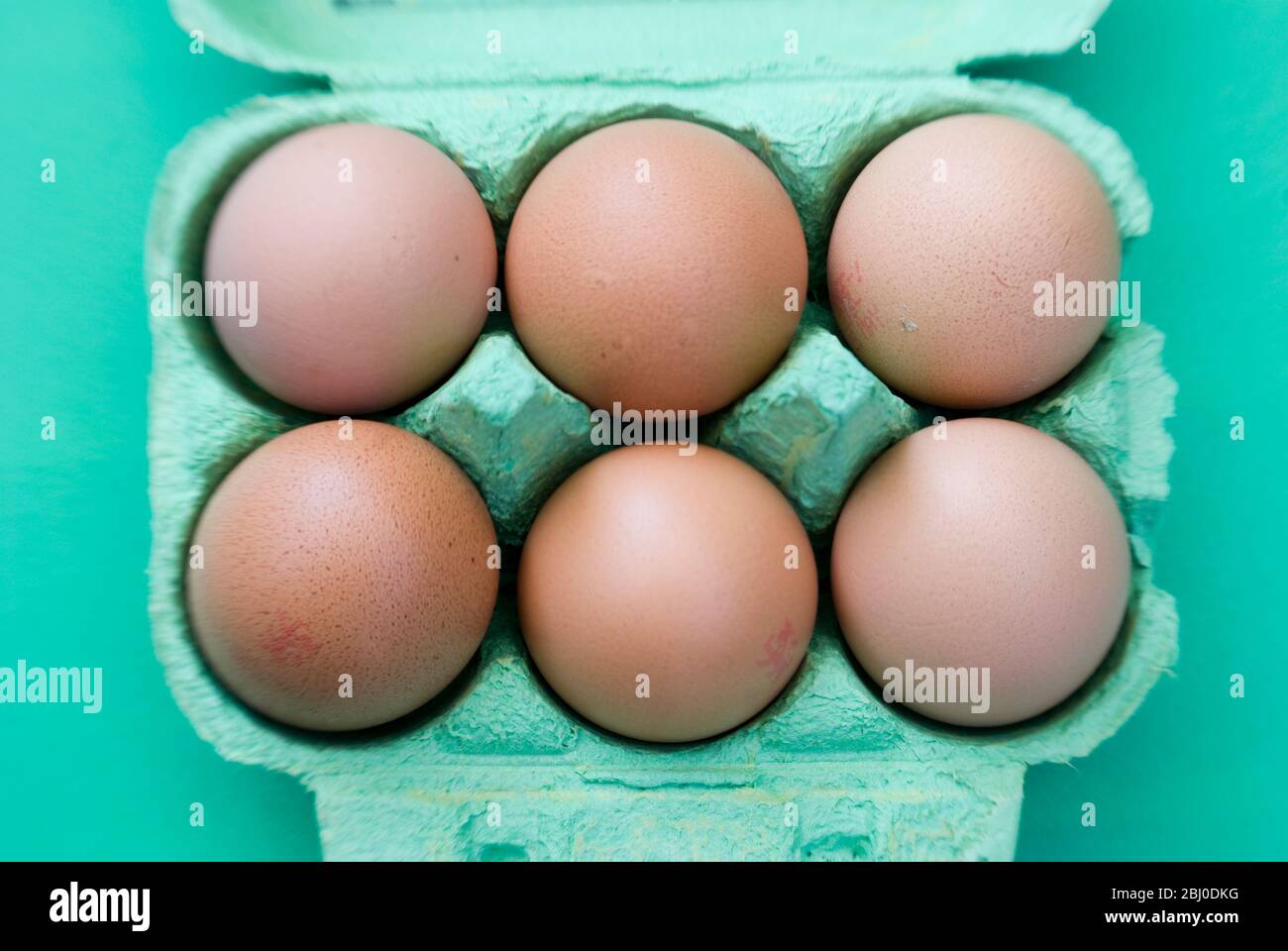 Half a dozen free range brown eggs in green egg box. - Stock Photo