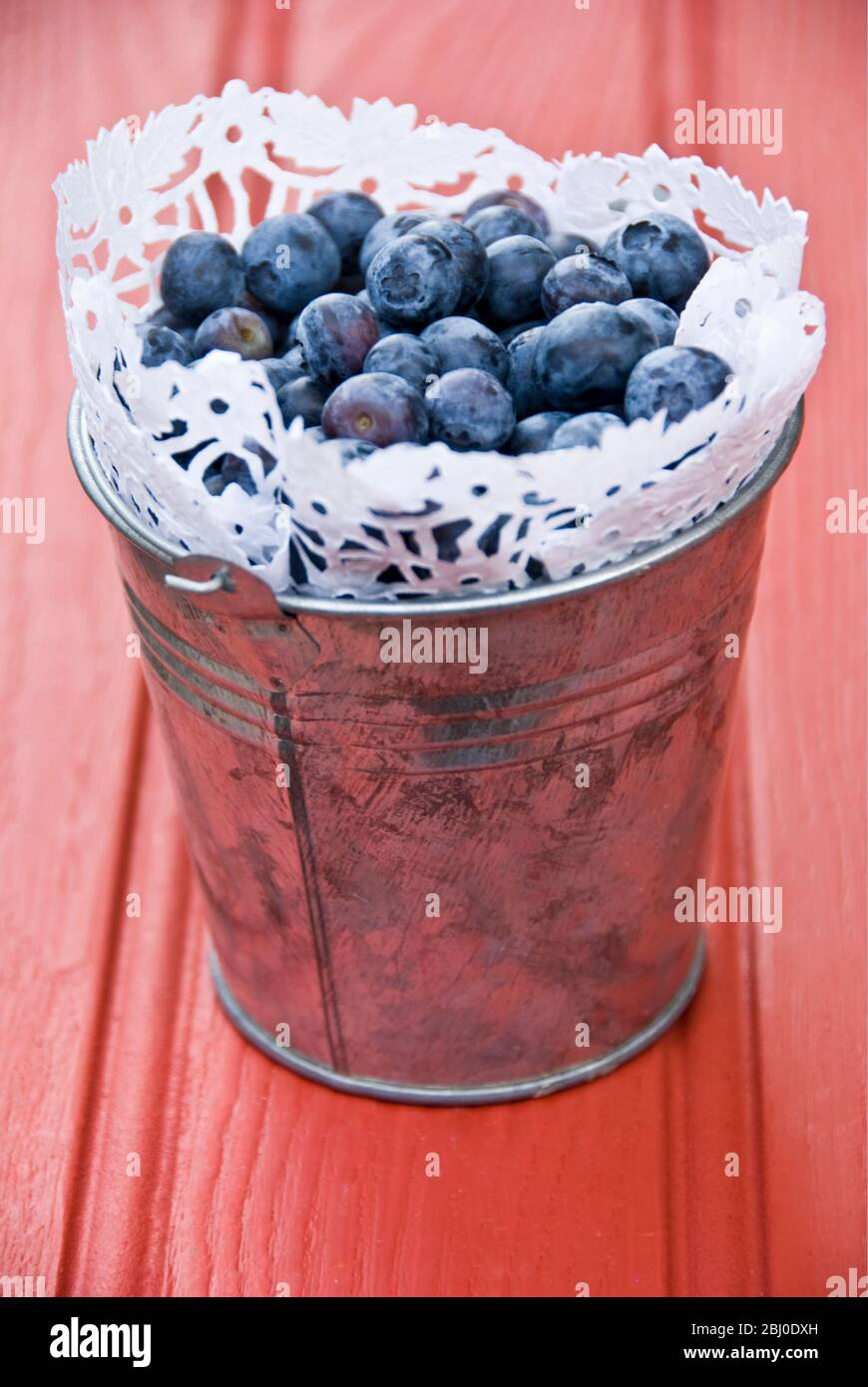 Fresh blueberries in metal bucket with paper doiley - Stock Photo