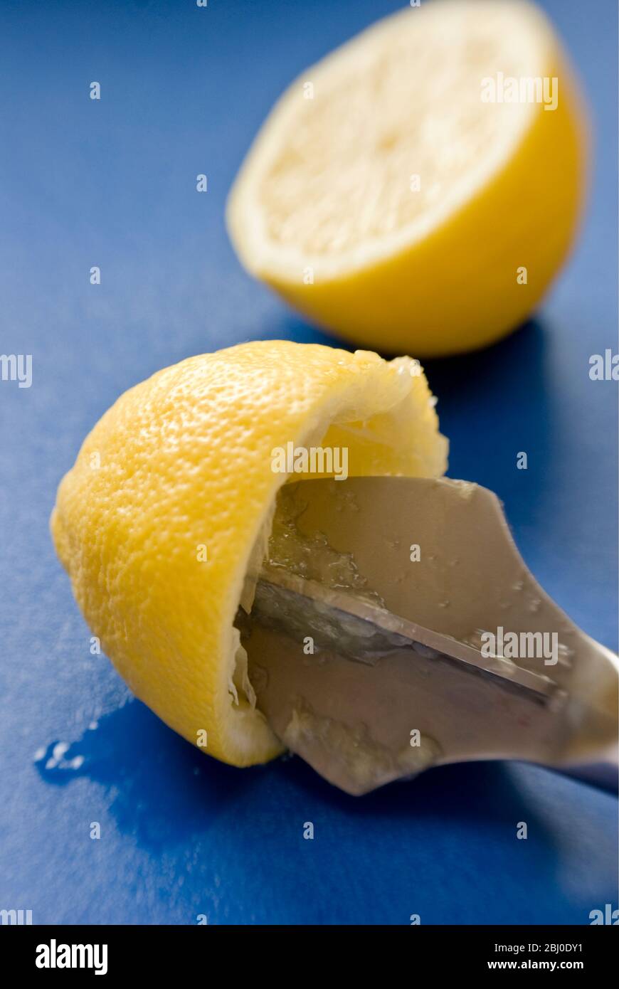 Squeezing halved elmon with reamer on blue surface - Stock Photo