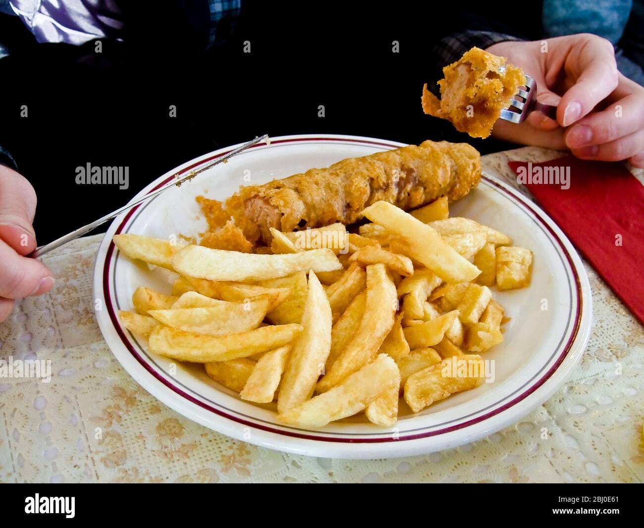 Deep fried, battered, sausage and chips, being eaten in English cafe - Stock Photo