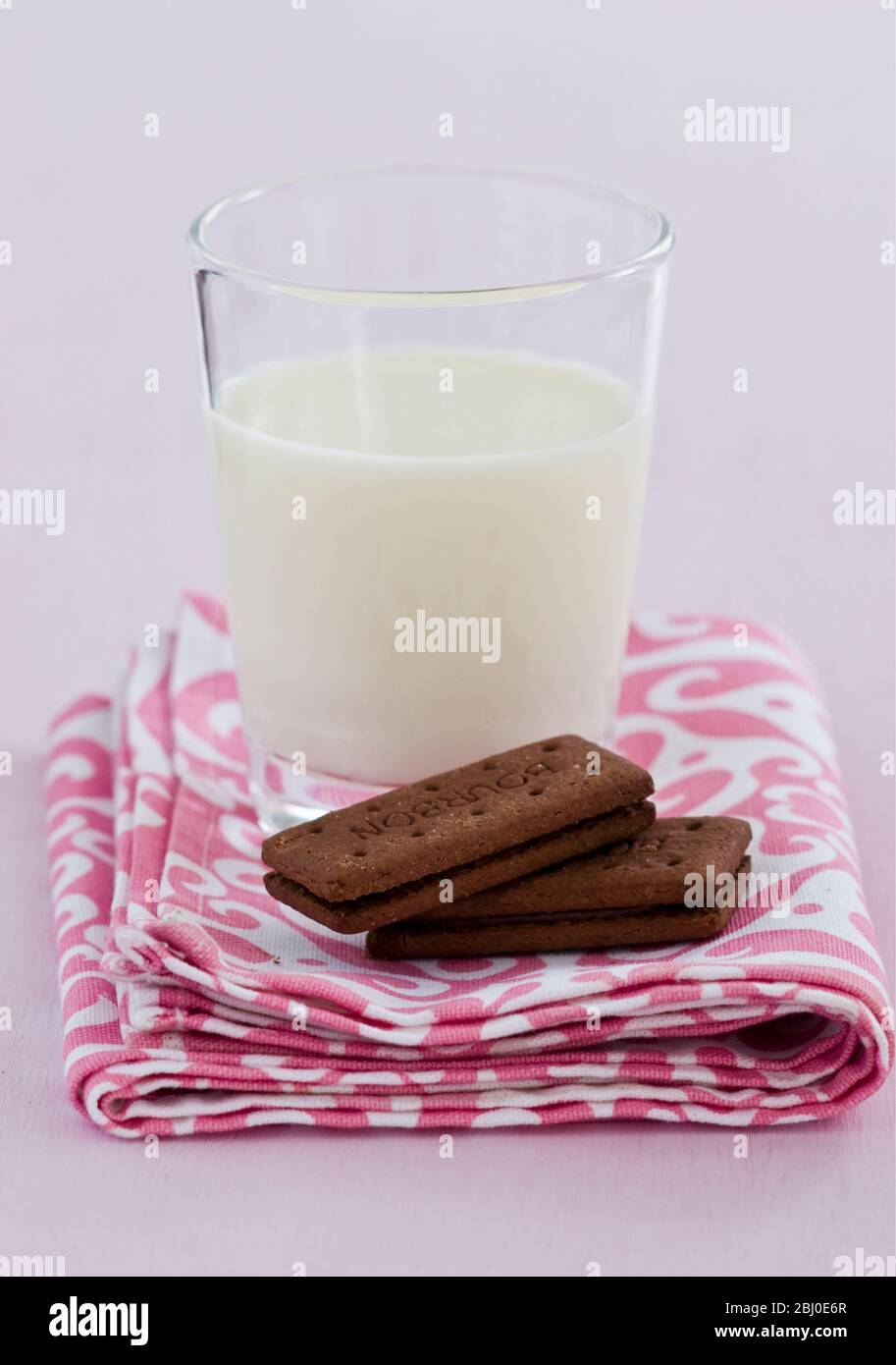 Bedtime snack of a glass of cold fresh milk with bourbon chocolate biscuits - Stock Photo