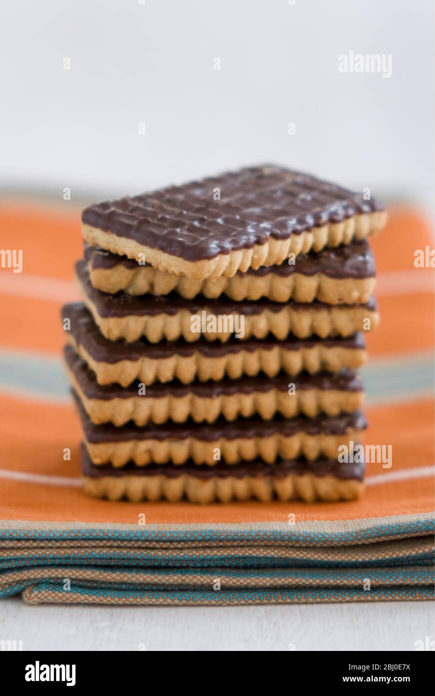 Stack of chocolate ginger biscuits on orange napkin - Stock Photo