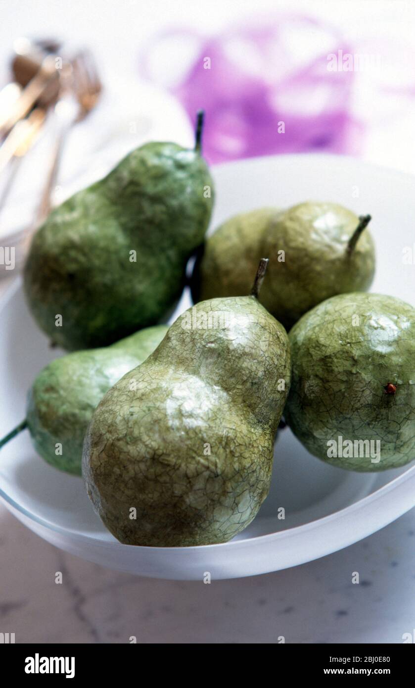 Decorative gren pears made from papier mache with crackle glaze, in glass bowl - Stock Photo
