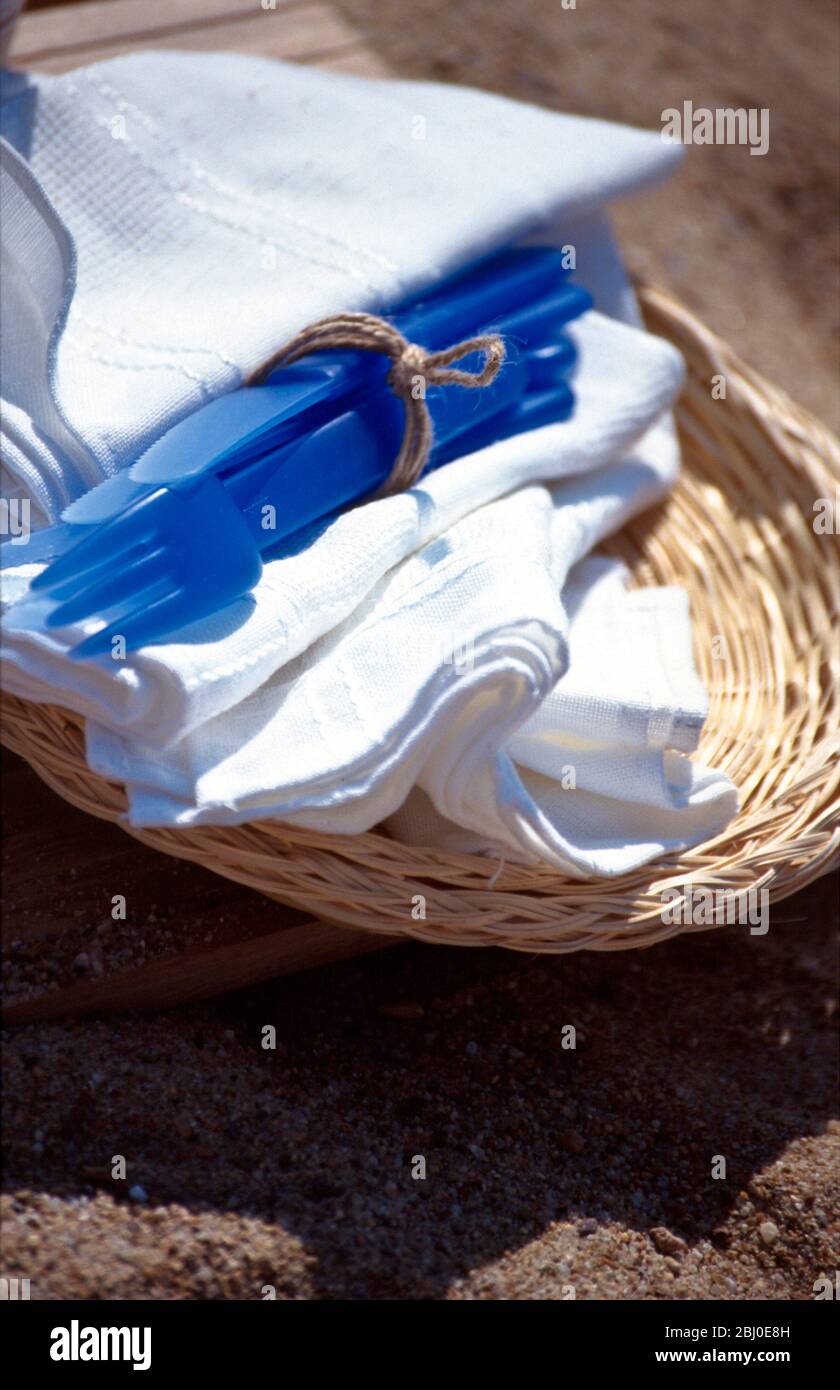 Basket tray with napkins and plastic cutlery on beach for summer picnic - Stock Photo