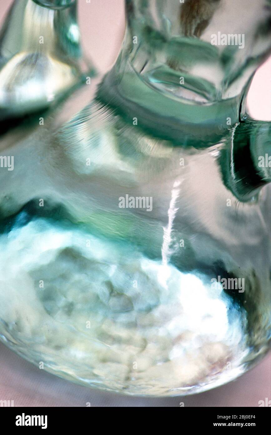 Close up of glass bottle full of water, emphasising greem tinge and texture of glass - Stock Photo