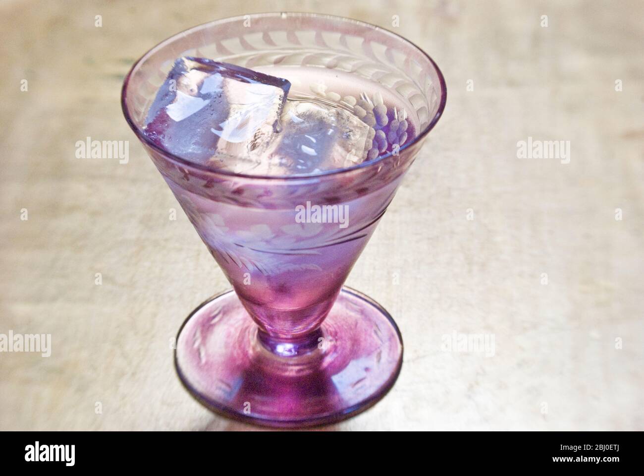 Small decorative glass of vodka on the rocks, on gold leaf tray - Stock Photo