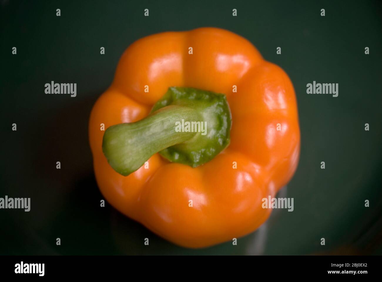 Orange pepper on dark green plate - Stock Photo