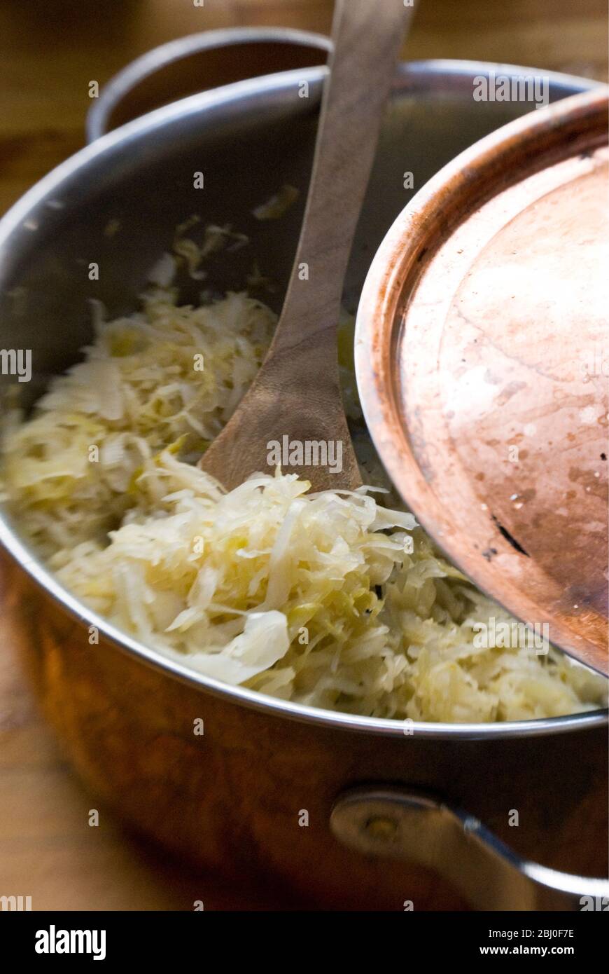 Copper pan with sauerkraut and wooden spoon - Stock Photo