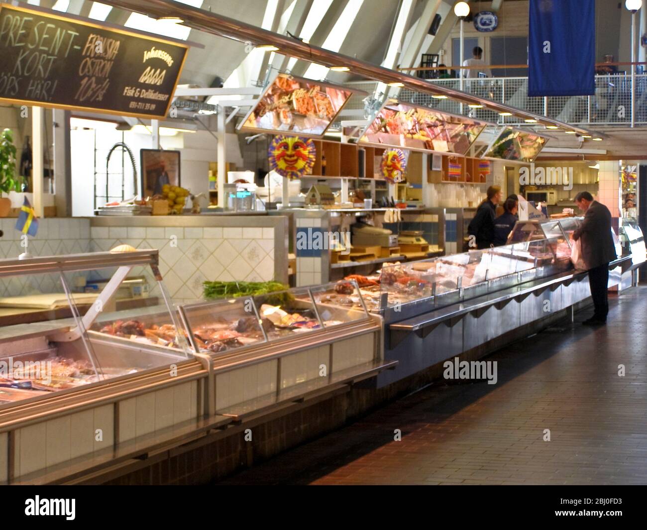 Interior of the 'Feske Kšrka' (Fish Church), the main fish market in Gothenburg, Sweden, showing fish stalls and shoppers. - Stock Photo