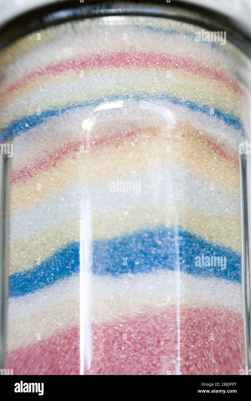 Detail of French jar of sugar with pastel coloured crystals of sugar arranged in separate layers - Stock Photo