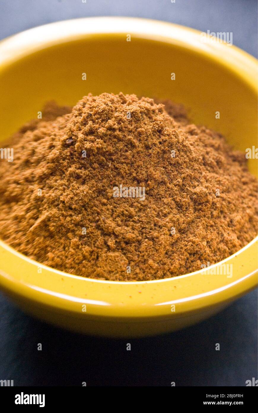 Ras-el-harnout (North African spice mixture), in small yellow bowl - Stock Photo
