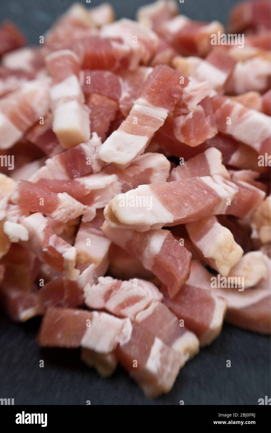 Chopped pieces of streaky bacon known as pancetta in Italy and lardons in France - Stock Photo