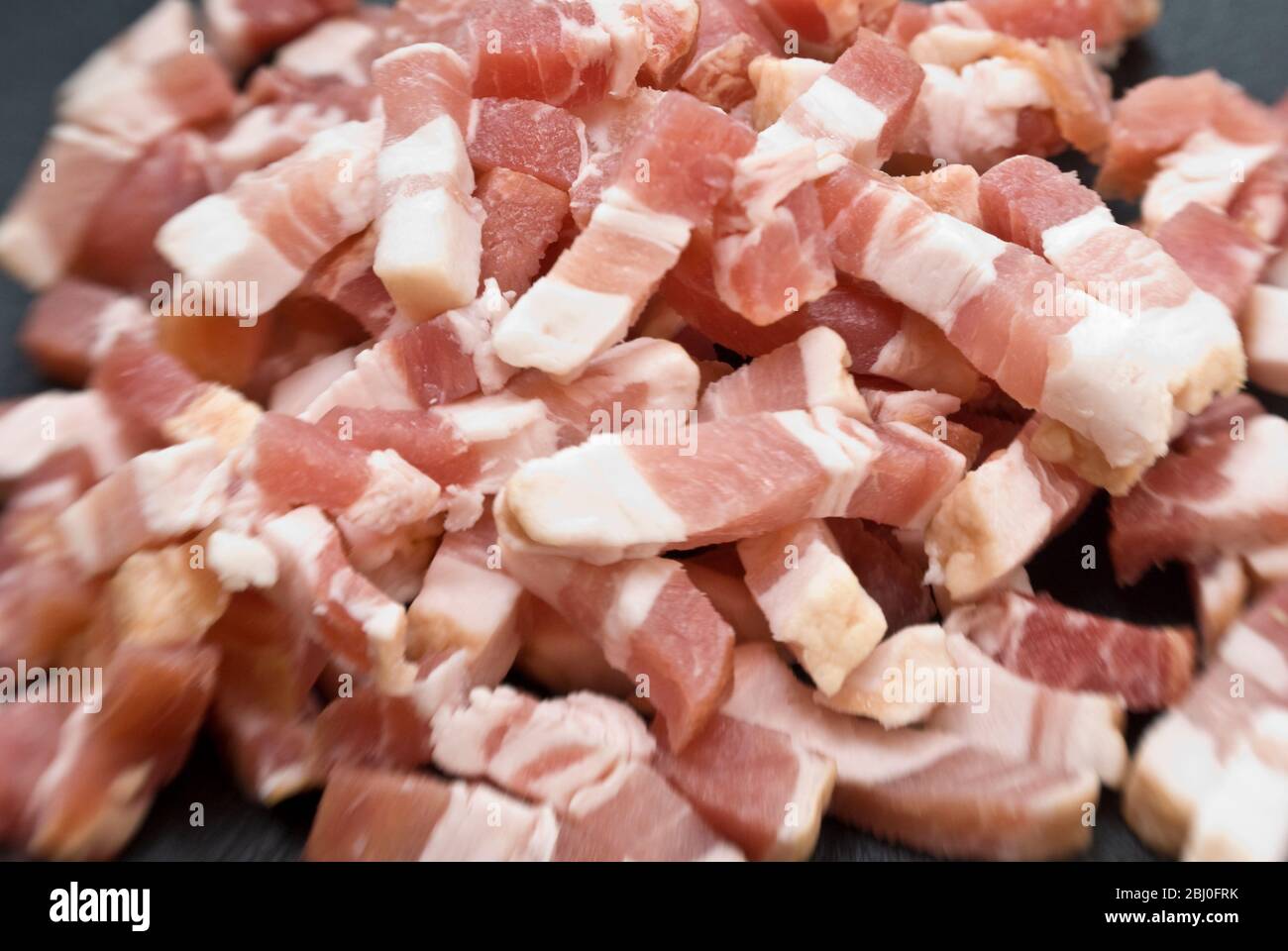 Chopped pieces of streaky bacon known as pancetta in Italy and lardons in France - Stock Photo