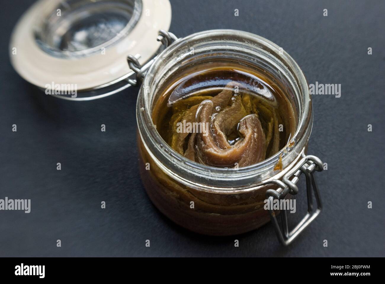 Fillets of anchovies in oil in preserving jar. - Stock Photo
