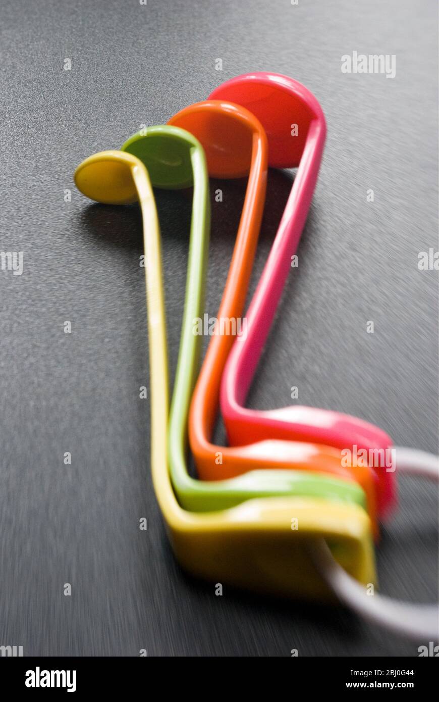 Set of brightly coloured melamine plastic measuring spoons - Stock Photo