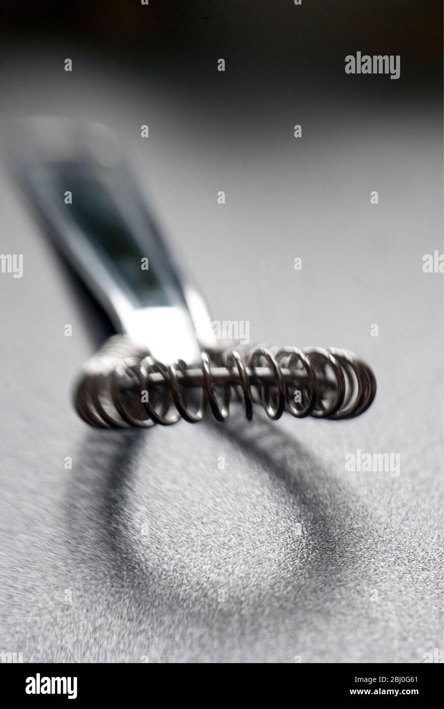 Wire whisk for cookery on dark surface - Stock Photo