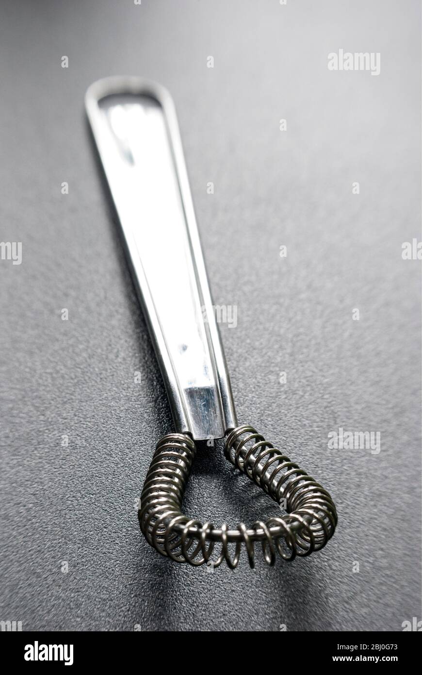 Wire whisk for cookery on dark surface - Stock Photo