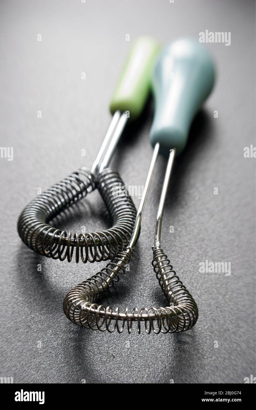 Wire whisks for cookery on dark surface - Stock Photo