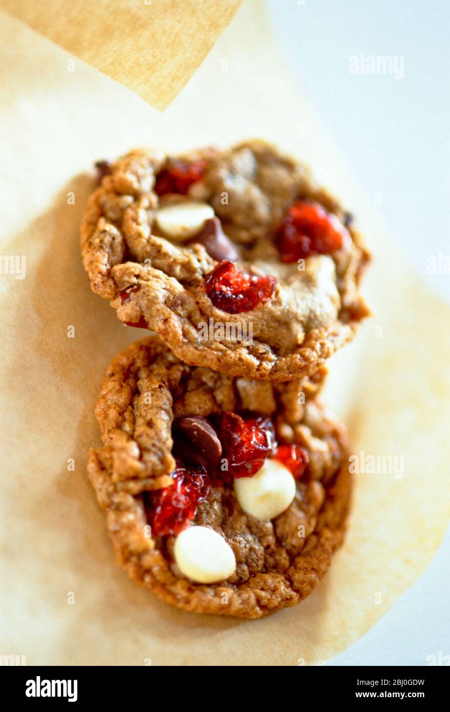 Cranberry and peanut and chocolate chip cookies on greaseproof paper - Stock Photo