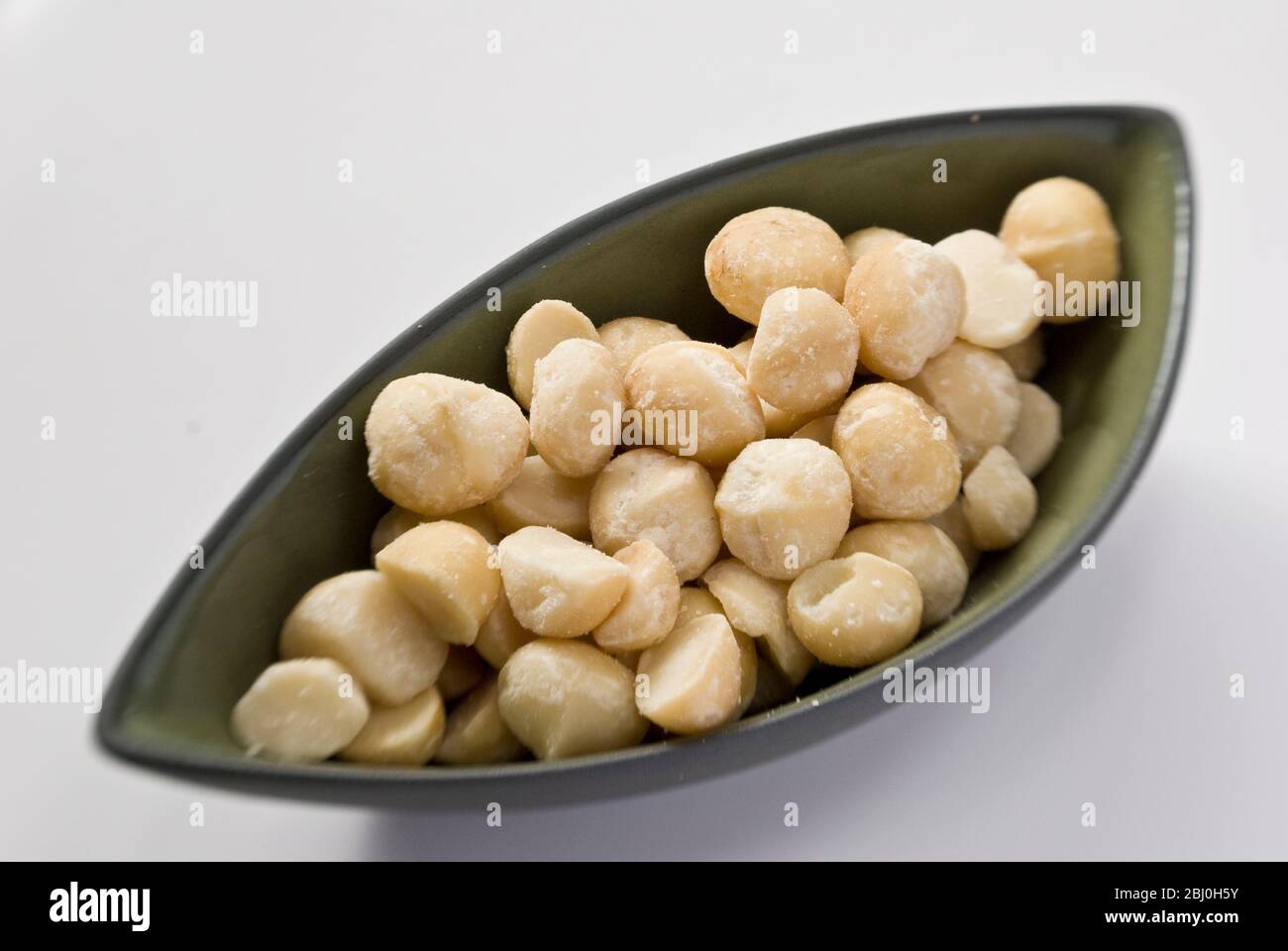 Shelled dry roasted macadamia nuts in bowl - Stock Photo