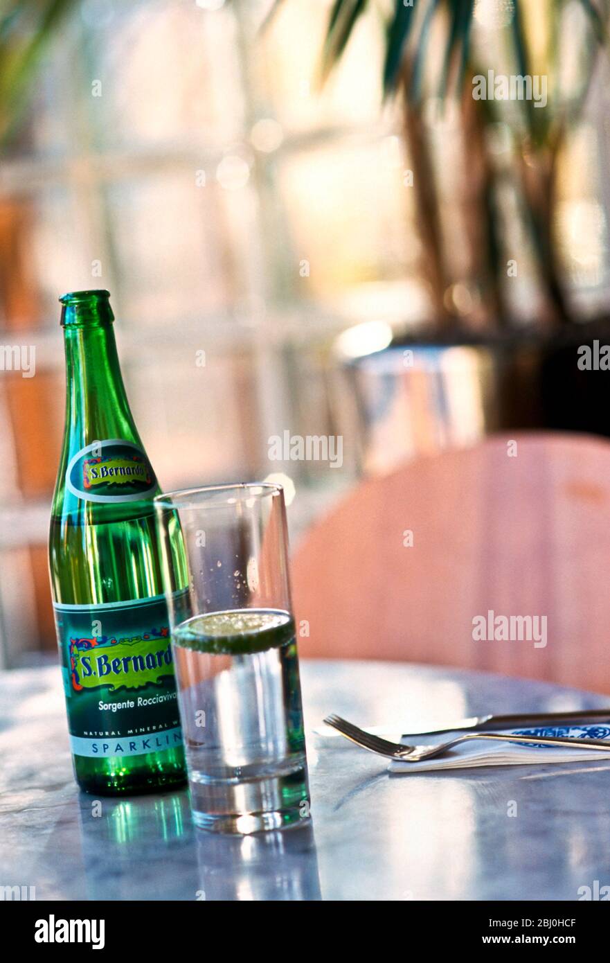 Bottled Italian fizzy water on marble topped table in restaurant Stock