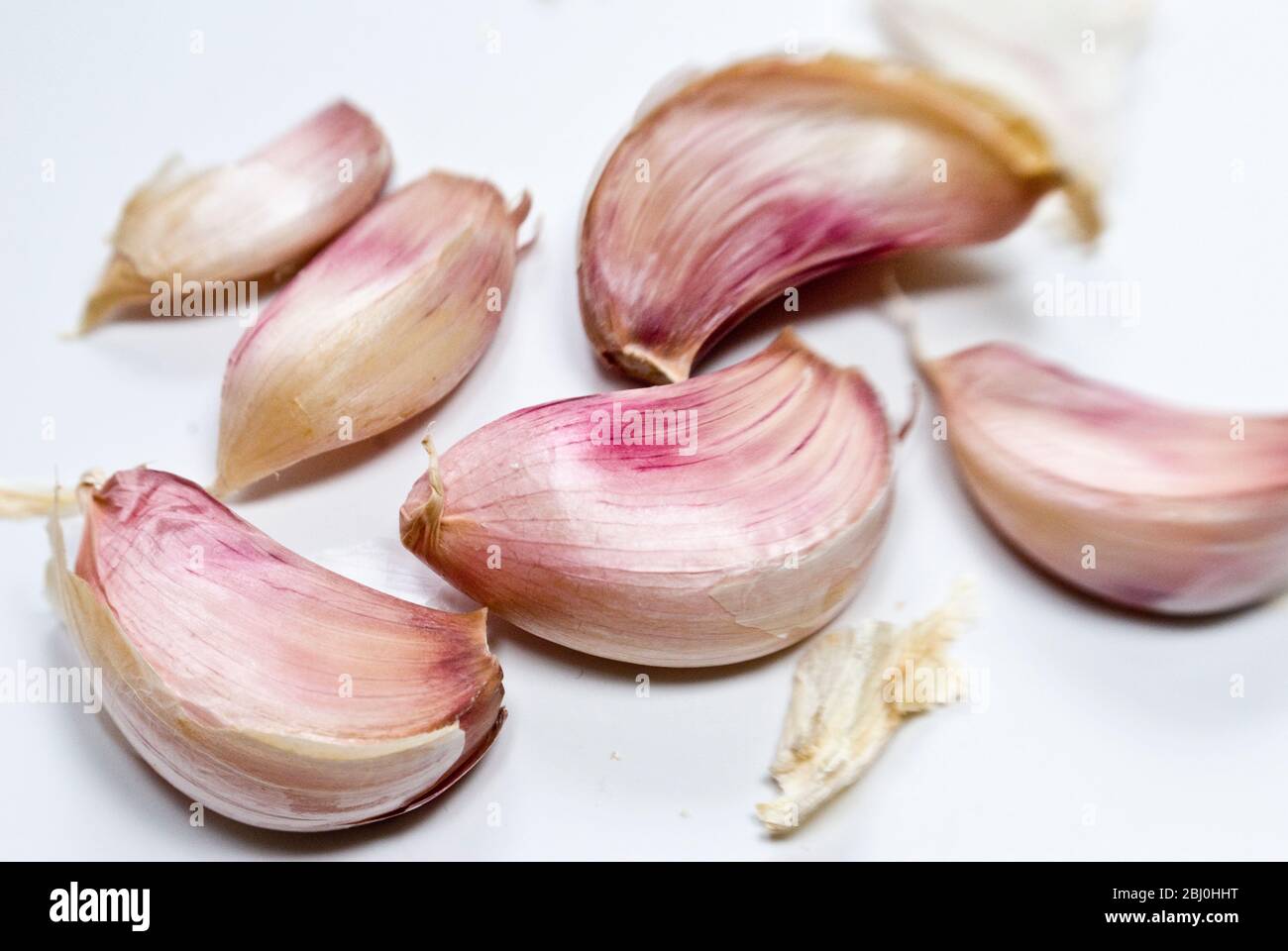 Cloves of garlic in their papery pink and white skins - Stock Photo